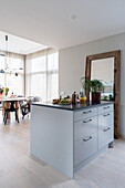 Kücheninsel mit grauen Fronten und Spiegel an der Wand in offenem Wohnraum