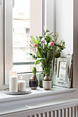 Frühlingsstrauß mit Tulpen und weiße Kerzen auf Fensterbank