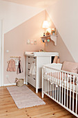 Babyzimmer mit Bettchen und Wickelkommode in Weiß und Rosa