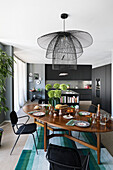 Covered, oval dining table, above it a black metal hanging lamp in an open-plan living room