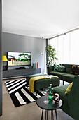 Grünes Ecksofa, Beistelltisch, Ottoman, Hängeboard und Fernseher im Wohnzimmer