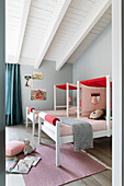 Partially covered beds in pink and red in the sibling room