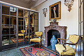 Pair of mustard upholstered armchairs at marble fireplace in 18th century mansion