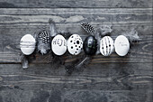 Black and white Easter eggs with feathers on a wooden background