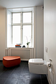 Toilette und orangefarbener Schemel im Badezimmer