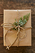 Gift wrapping made of wrapping paper, string, gift tag, and juniper branch