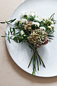 Posy of hydrangea, dahlia, carnation, roses and olive branch decorating plate