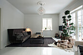 Geschmückter Baum, Weihnachtsgeschenke, braunes Sofa und Couchtisch im Wohnzimmer