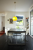 Dining table and classic chairs below pendant lamp with yellow lampshade
