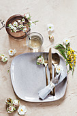 Tisch- und Tellerdekoration mit Mimiosen, Rosenblüten, Narzissenblüten und Waxflower