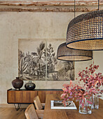 Dining table, pendant lights above, view of large print picture above sideboard