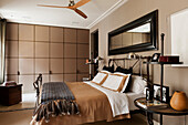 Bed with metal and leather frame in bedroom with built in storage and ceiling fan