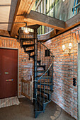 Metal spiral staircase in foyer with brick wall