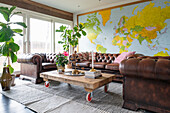 Classic leather suite, pallet table on castors and world map on wall in living room