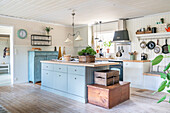 Light blue kitchen island in eat-in kitchen with wooden floorboards