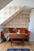 Brown couch and coffee table against wall with tartan wallpaper
