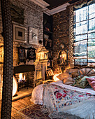 Schlafzimmer mit Batik-Vorhang, Kamin und Backsteinwand