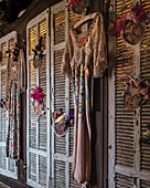 Vintage dresses and jewelled masks on reclaimed shutters