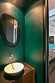 Gästetoilette mit Waschbecken und Spiegel an grüner Wand