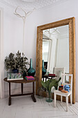 Großer Spiegel an die Wand gelehnt, Holzstuhl und Tisch in Zimmerecke