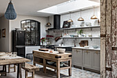 Open plan sophisticaed kitchen with vintage brass pendant lighting, rustic wooden butchers island and beaded chandelier
