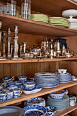 Blue and white china and silverware on wooden shelves in Georgian home