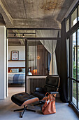 Klassiker Lounge Chair vor Terrassentür in einem Loft, im Hintergrund Schlafzimmer