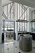 Round kitchen sink in elegant high-ceilinged kitchen with interior windows