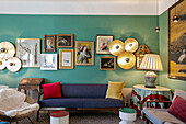 Seating, old artwork and modern wall lights in lounge with green walls