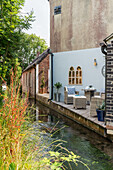 Sitting area with wicker chairs on small terrace at the house by the canal