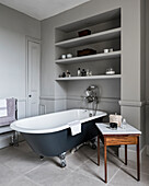 Freistehende Badewanne unterm Regal im klassischen Bad in Grau
