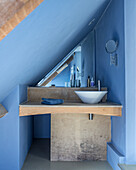 Blaues Badezimmer unter dem Dach mit speziell angefertigten Holzeinheiten