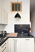 L-shaped fitted kitchen with light fronts and black worktop