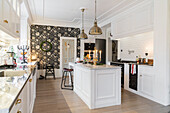 Open, white kitchen with kitchen island and a statement wall with wallpaper