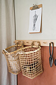 Baskets on wooden rail, above them art print on a clipboard hanging on the wall