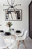 Round dining table and white classic chairs below pendant lamp