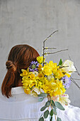 Woman carrying spring bouquet with daffodils on her shoulder