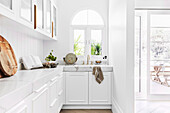 White fitted kitchen in L-shape with round arch window