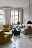 Sofa and designer armchair in living room of an old building with stucco mouldings