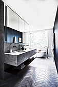 Maßgefertigter Waschtisch mit Carrara-Marmor, im Hintergrund freistehende Badewanne vor dem Fenster im Badezimmer