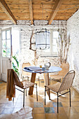 Round table with chairs and garden access in a room with a whitewashed brick wall