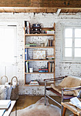 Chair with animal fur in front of shelves in a room with whitewashed brick wall