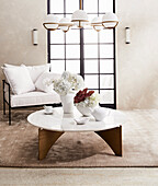 Vases on coffee table with marble top and designer chairs with white cushions