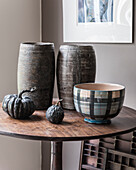 Zwei Holztöpfe aus Südafrika mit getrockneten Kürbissen und einer Schale auf rundem Tisch