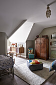 An attic bedroom with floor cushions and a wardrobe from the 1930s