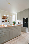 Classic kitchen with grey coffered cabinet fronts and wooden floorboards