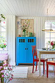 Red chairs around table and blue cupboard in the kitchen-dining room