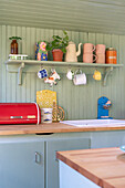 Vintage-style ornaments on wall-mounted shelf in rustic kitchen