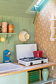 Portable gas hob in colourful retro kitchen with mint green wall panelling