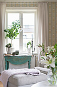 Turquoise console table below window with houseplant on sill